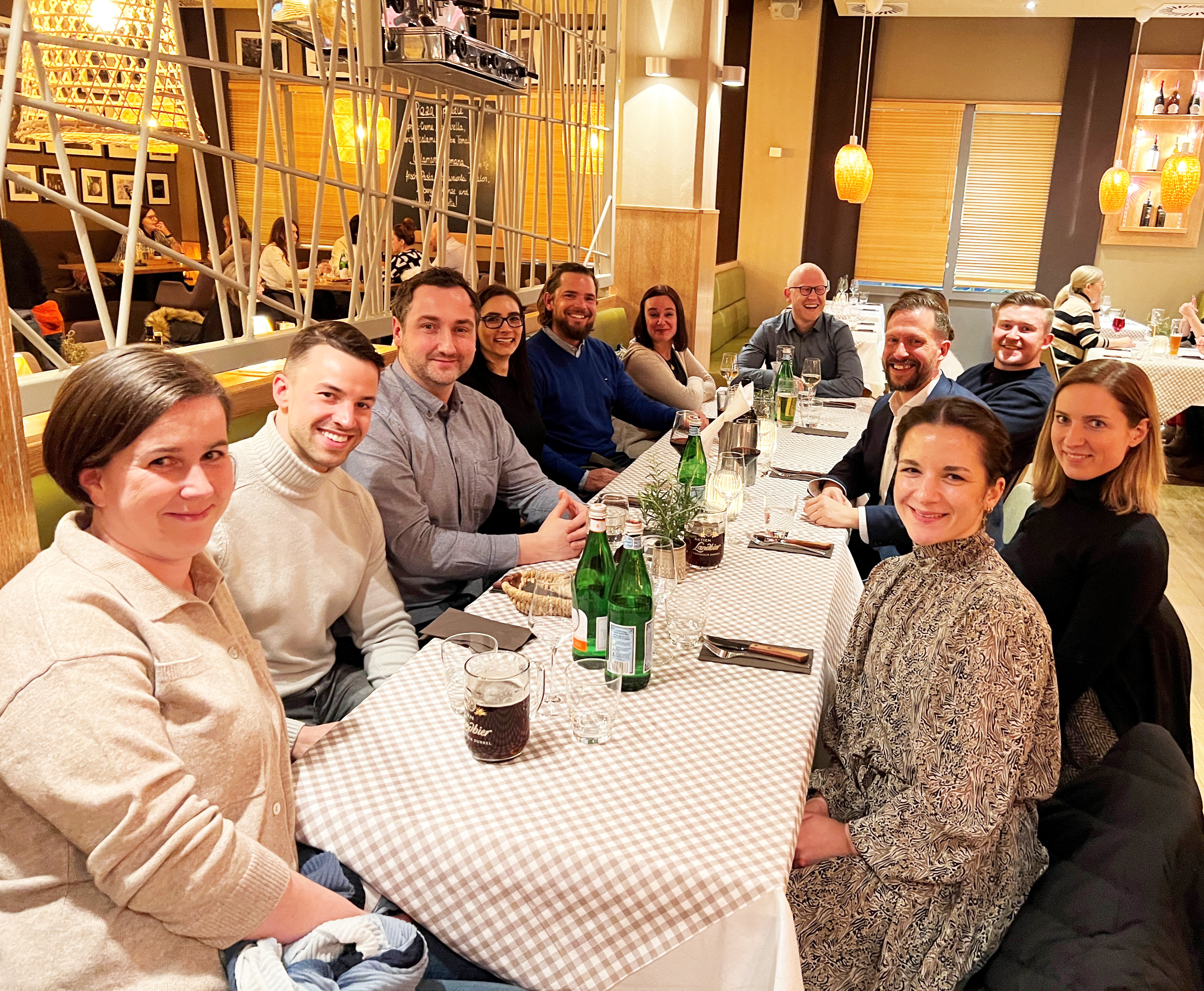 Die Studierenden des MBA Verantwortung, Führung und Kommunikation sitzen in einem Restaurant an einem Tisch zum Abendessen beisammen
