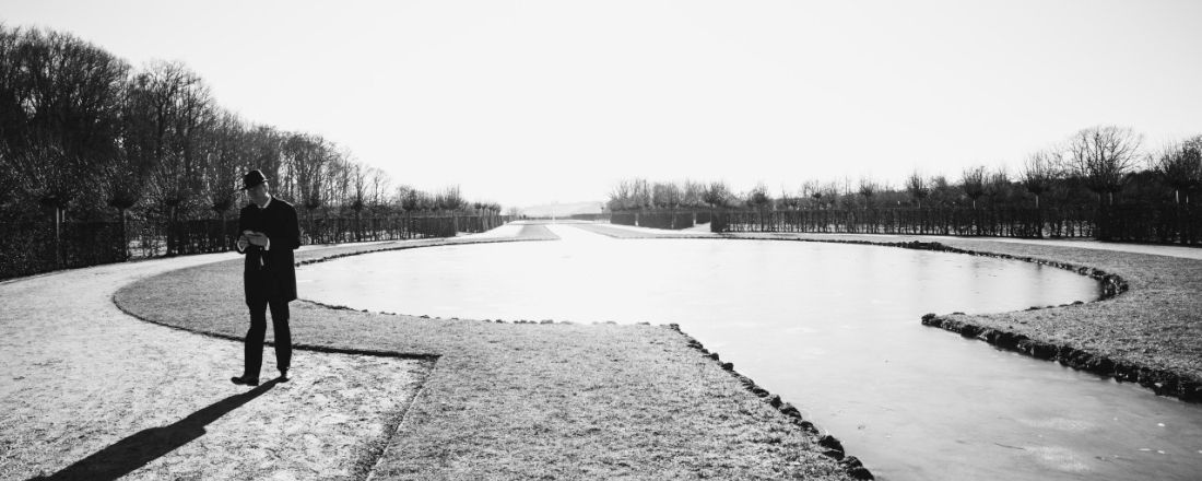 Schwarz-Weiß-Aufnahme von Prof. Dr. Germelmann in einem weitläufigen Park mit Brunnen und Allee