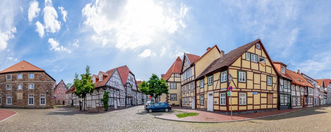 Innenstadt mit Fachwerkhäusern, Bäumen und Autos sowie einer gepflasterten Straße