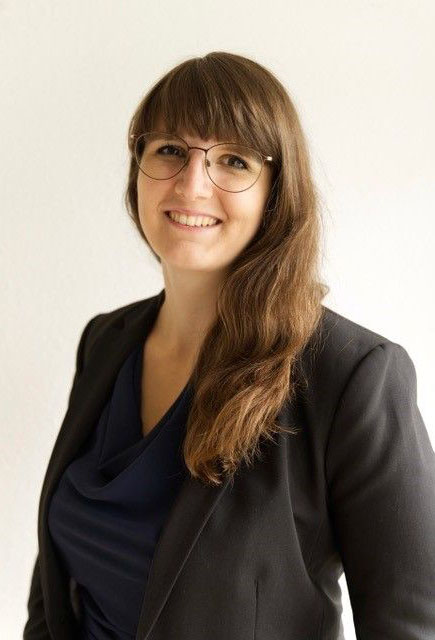 Auf dem Bild zu sehen ist Nathalie Krebs, die Gewinnerin des medhochzwei Stipendiums 2023. Sie hat lange braune Haare, trägt eine Brille sowie ein schwarzes TShirt und Blazer